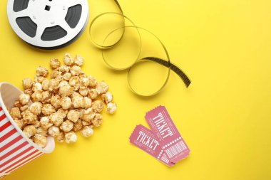 Film biletleri, patlamış mısır ve sarı arka planda film makarası.