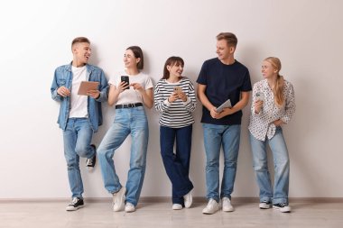 Beyaz duvarın yanında farklı aletler kullanan bir grup insan. Modern teknoloji