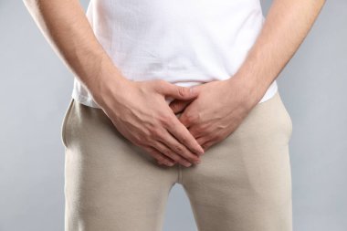 Cinsel yolla bulaşan hastalıklar. Gri arka planda semptomlardan muzdarip bir adam, yakın plan