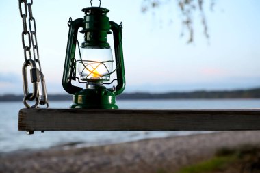 Vintage kerosene lamp on swing at beach in evening