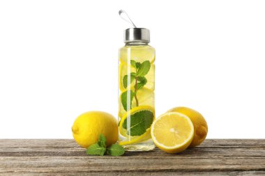 Şişe içinde naneli limon suyu ve tahta masada beyaz arka planda taze meyveler.