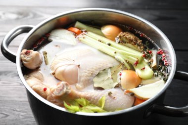 Tam çiğ hindi, soğan, kereviz ve baharatlar siyah ahşap masada, yakın plan.