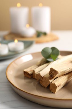Palo santo sopaları ve okaliptüs yaprakları beyaz ahşap masada, yakın plan.