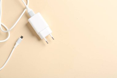 Bej arka planda şarj kablosu olan USB güç adaptörü, üst görüntü. Metin için boşluk