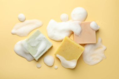 Sarı arka planda köpüklü sabun çubukları, düz yatış