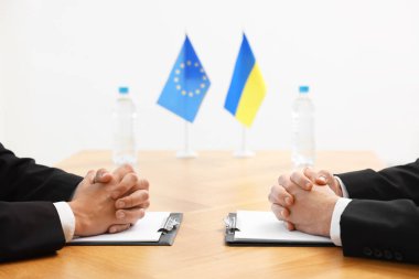 Diplomatlar ahşap masada toplantı yaparken yakınlaşıyorlar.