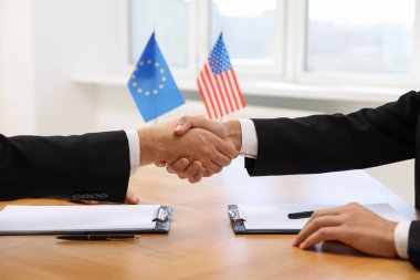 Diplomatlar ahşap masada toplanırken el sıkışıyorlar.