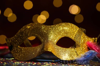 Güzel bir karnaval maskesi ve koyu arkaplanda bulanık ışıkları olan konfeti, yakın plan.