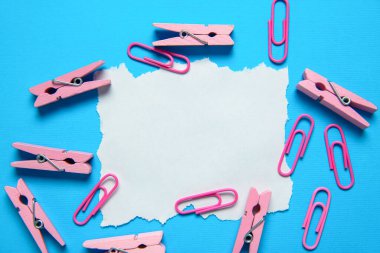 Boş not, elbise askıları ve açık mavi arka planda ataçlar, düz yatış. Metin için boşluk