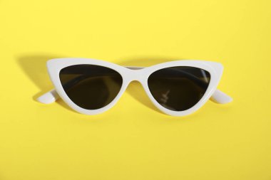 Sarı arka planda şık güneş gözlükleri. Zarif aksesuar.