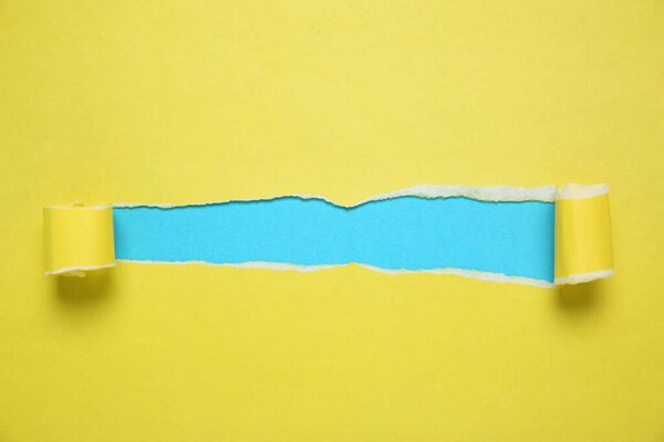 Желтая бумага с разорванной дырой на голубом фоне, вид сверху. Пространство для текста