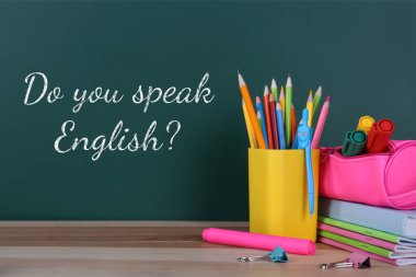 İngilizce konuşabiliyor musun? Yeşil karatahta ve ahşap masadaki kırtasiye malzemeleri. Dil kursu