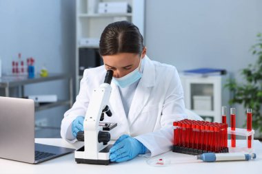 Laboratuvar testi. Doktor, mikroskopla kapalı bir masada çalışıyor.