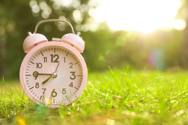 Yeşil çimlerin üzerindeki pembe alarm saati. Metin için boşluk