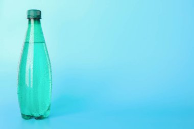 Açık mavi arka planda plastik su şişesi. Metin için boşluk