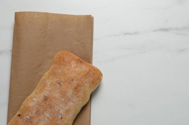 Kağıt torba ve beyaz mermer masa üzerinde taze ciabatta, üst manzara. Metin için boşluk