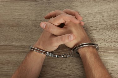 Ahşap masada metal kelepçeli bir adam var.