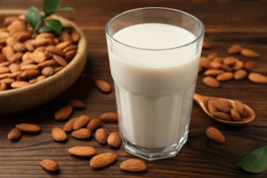 Bardakta taze badem sütü ve ahşap masada fındık, yakın plan.