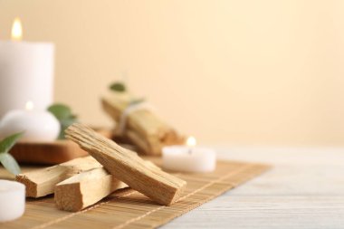 Palo Santo sopaları ve yanan mumlar açık ahşap masada, yakın plan. Metin için boşluk