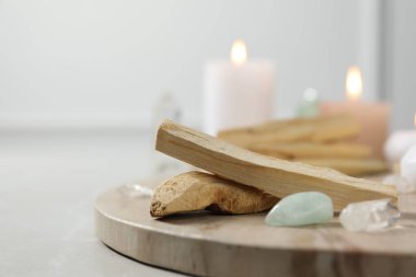 Palo Santo çubukları, değerli taşlar ve yanan mumlar ışık masasında, yakın plan