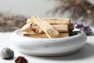 Palo Santo sopaları ve değerli taşlar beyaz masada, yakın plan.