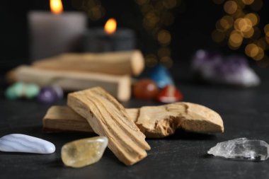 Palo santo sopaları, değerli taşlar ve siyah masada yanan mumlar bulanık ışıklara karşı, yakın çekim