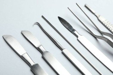 Açık gri arka planda farklı cerrahi araçlar, yakın plan
