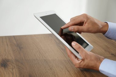 İşadamı ahşap masada tablet kullanıyor, yakın plan. Modern teknoloji