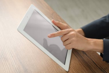 İş kadını, kapalı bir masada tablet kullanıyor, yakın plan. Modern teknoloji