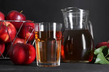 Lezzetli taze elma suyu ve siyah ahşap masada meyveler.