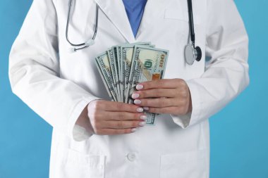 Yozlaşma konsepti. Açık mavi arka planda dolar banknotları olan doktor, yakın plan.