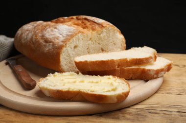 Tahta masada tereyağı ve bıçakla taze ekmek, yakın plan.