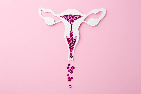 Menstruation. Paper uterus with sequins on pink background, top view