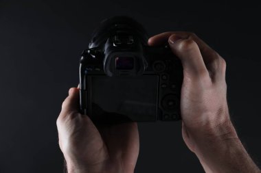 Koyu arkaplanda profesyonel kameralı fotoğrafçı, yakın plan.