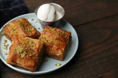 Ahşap masada ezilmiş fındıklı ve dondurmalı enfes baklava, yakın plan. Metin için boşluk