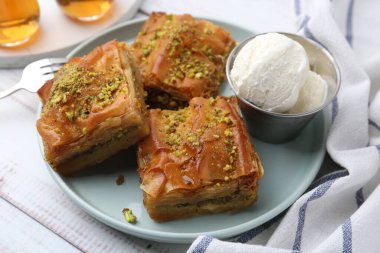 Hafif ahşap masada ezilmiş fındıklı ve dondurmalı enfes baklava, yakın plan.