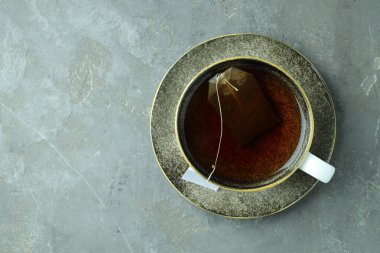 Çay poşeti içinde sıcak içecek, gri desenli masa, üst manzara. Metin için boşluk