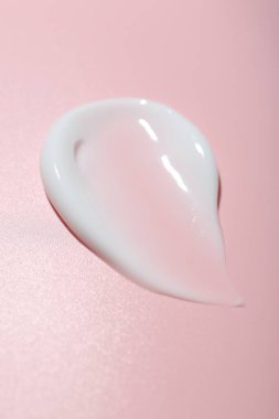Pembe arka planda krema örneği, yakın plan. Cilt ürünleri