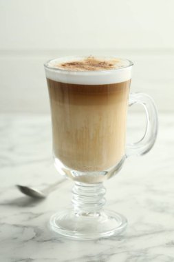 Cam bardakta latte macchiato, beyaz mermer masada, yakın plan.