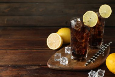 Tahta masada limon dilimleri olan taze buzlu kola. Metin için boşluk