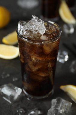 Taze buzlu kola ve limon dilimleri koyu gri masada, yakın plan.
