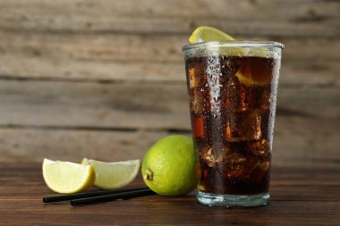 Limon dilimli buzlu kola ve ahşap masada limon, yakın plan. Metin için boşluk