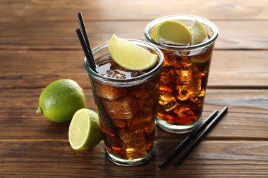 Limon dilimli buzlu kola ve ahşap masada limon, yakın plan.