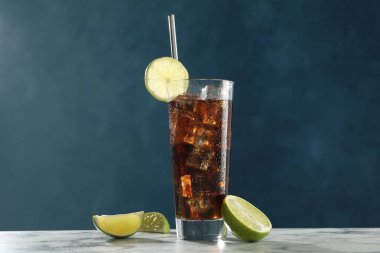 Beyaz mermer masadaki limon dilimli buzlu kolayı mavi arkaplana karşı tazeliyorum.