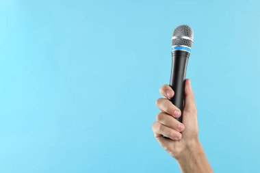 Açık mavi arka planda mikrofonu olan adam, yakın plan. Metin için boşluk
