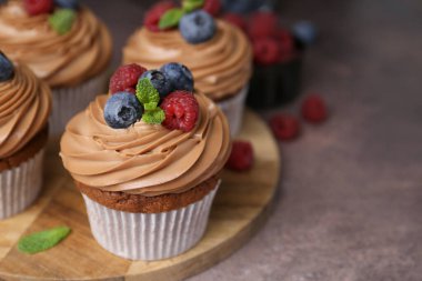 Kahverengi masada çikolatalı kremalı ve dutlu lezzetli kekler, yakın plan. Metin için boşluk
