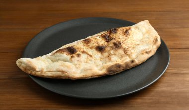 Ahşap masada lezzetli bir calzone tabağı, yakın plan.