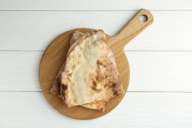 Beyaz ahşap masa üzerinde leziz calzone parçaları olan tahta, üst manzara.
