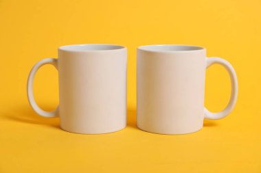 Turuncu arka planda damgalamak için iki boş kupa. Tasarım için model