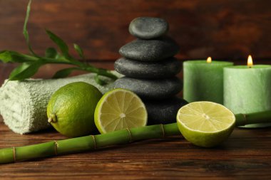 Taze limonlu spa kompozisyonu, çakıl taşları, yanan mumlar ve ahşap masada bambu, yakın plan.